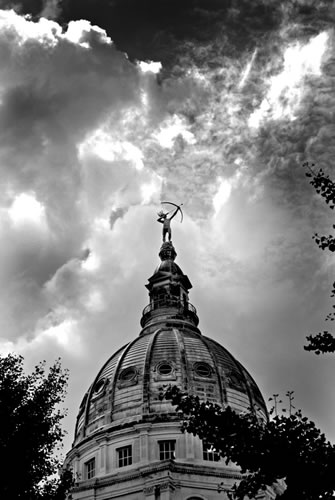 Black and white of drum and statue against partly cloudy sky